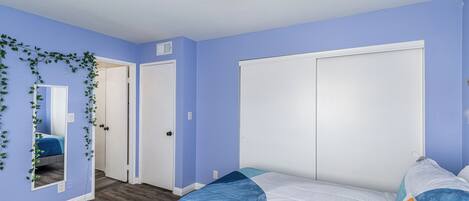 A bedroom with a bed, a ceiling fan, and a door.