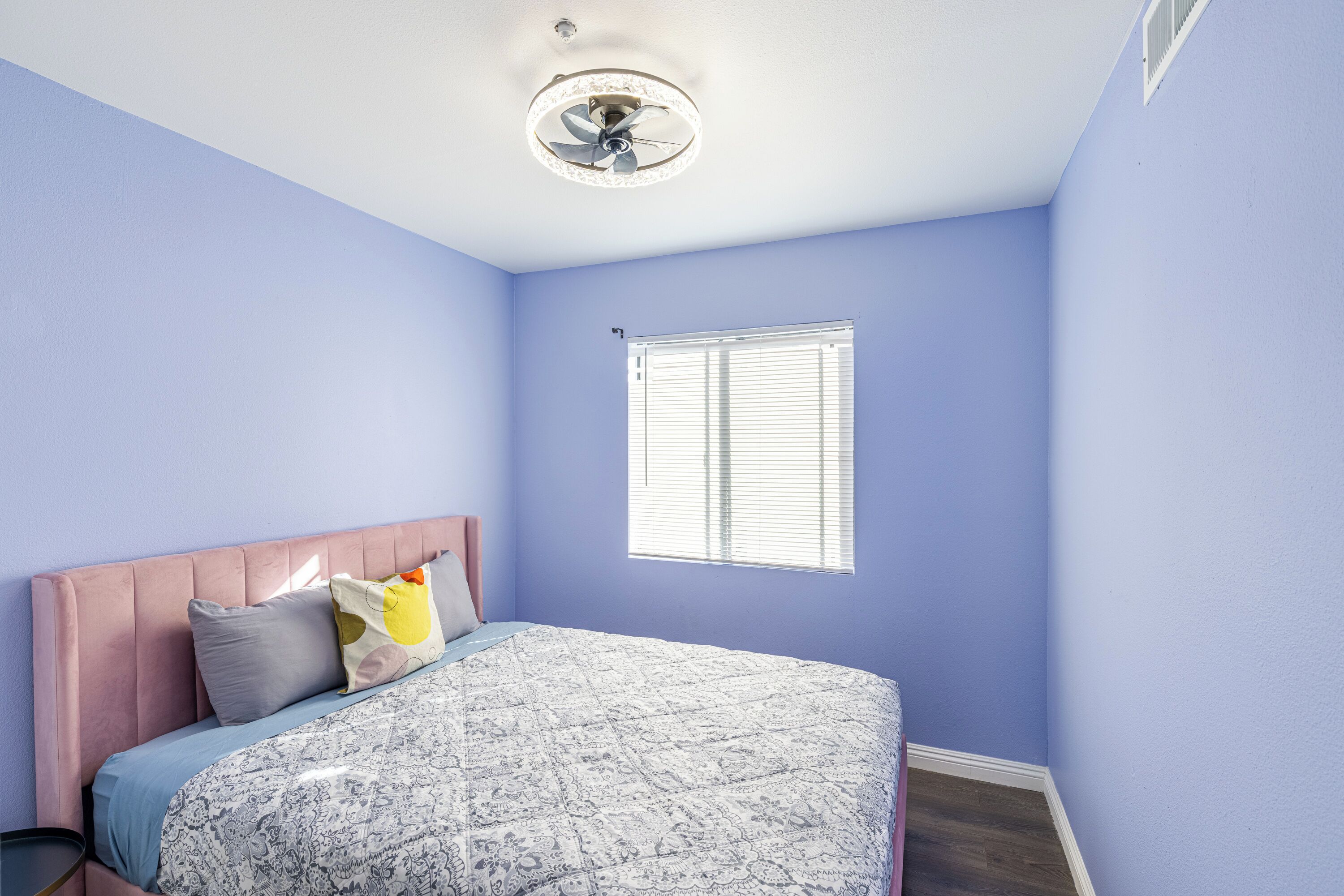 A bedroom with a bed, a window, and a ceiling fan.