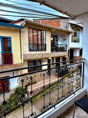 A residential building with a balcony, a tiled patio, and a motorcycle parked outside. - Rancho Alegre 3 Apartment (Salento)