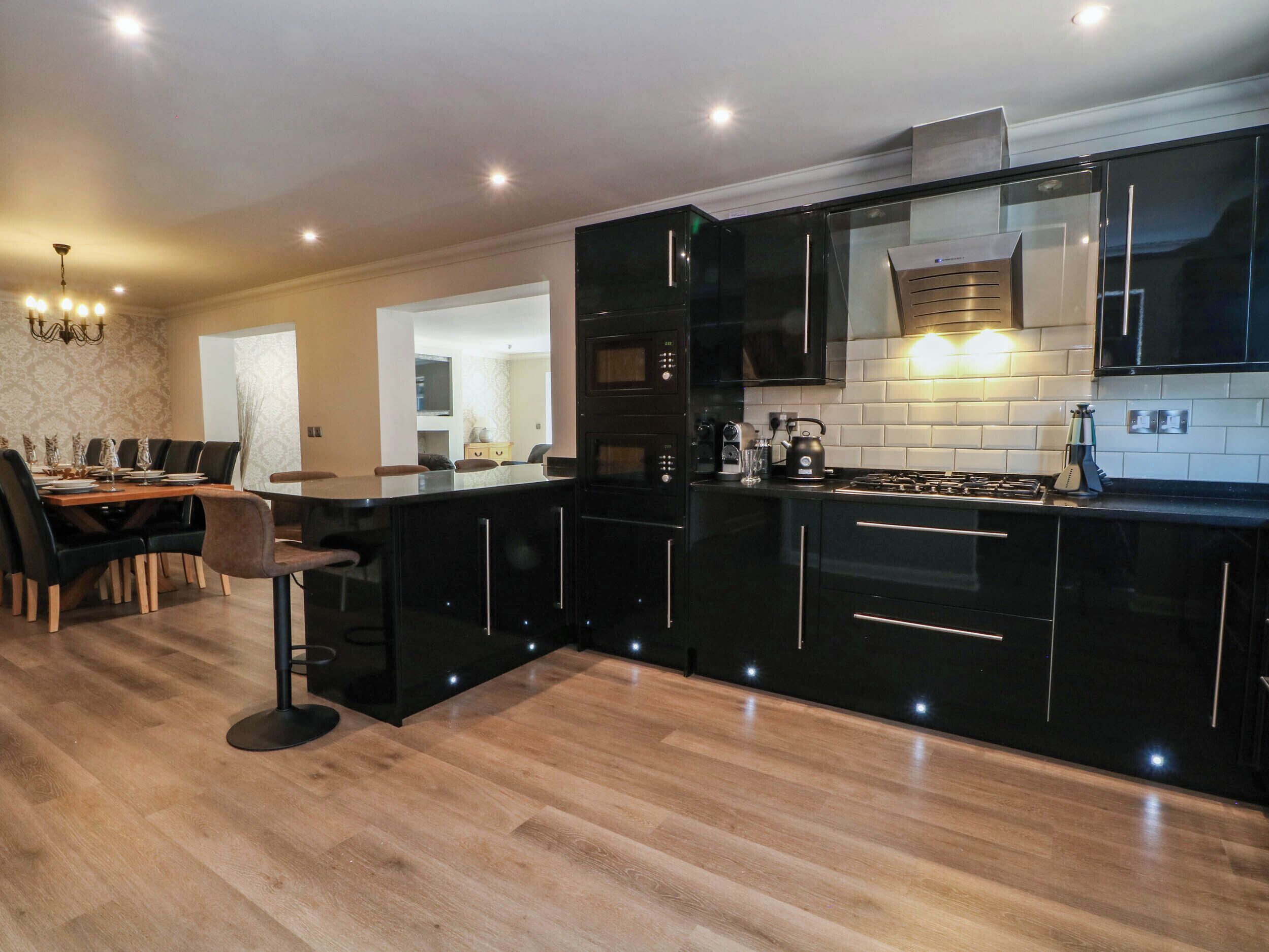 Una cucina moderna con mobili neri, un tavolo da pranzo in legno e un lampadario.