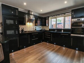 Una cocina moderna con armarios negros, piso de madera y ventana con vistas al exterior.