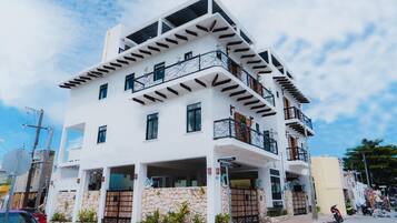 A multi-story building with balconies, a stone facade, and a clear sky.