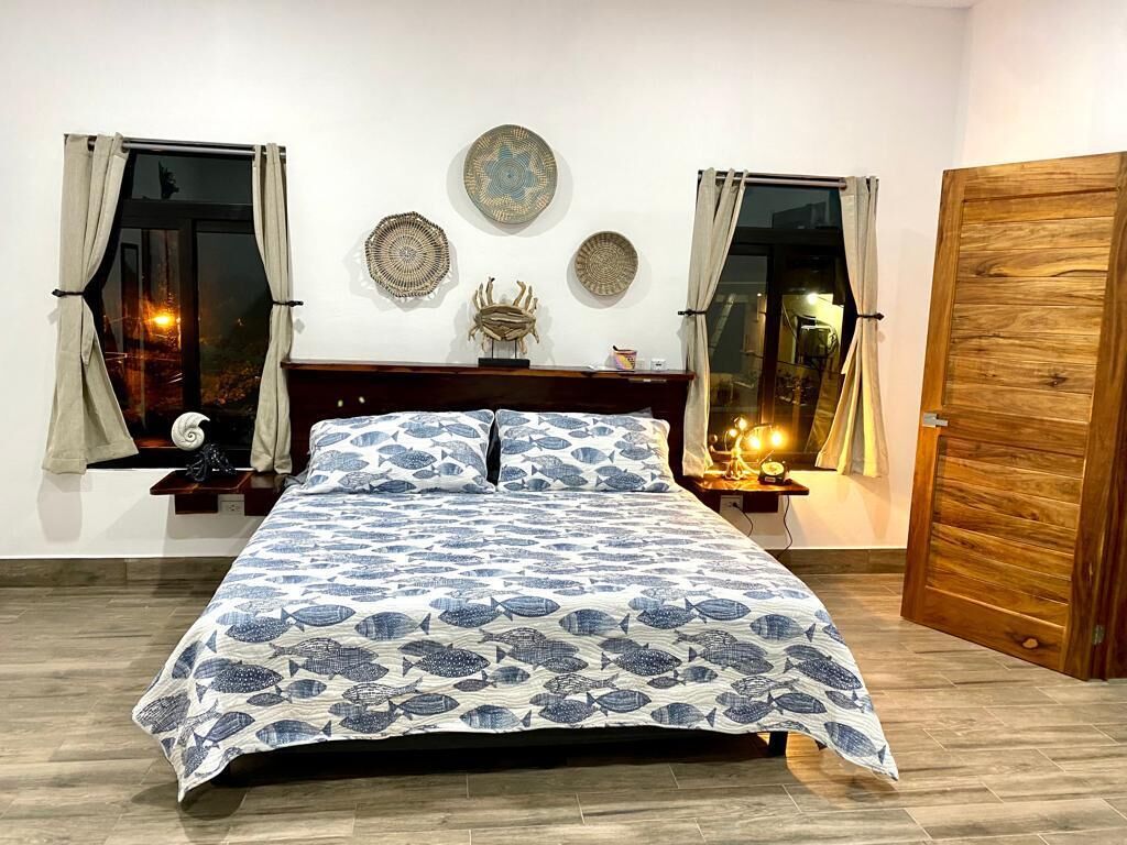Ein Schlafzimmer mit Bett, Vorhängen, Wanddekoration und einer Holztür.