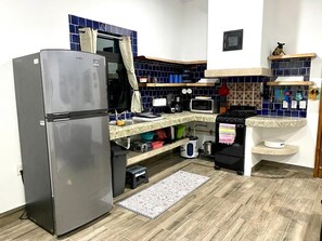 A compact kitchen with a refrigerator, microwave, and a sink.