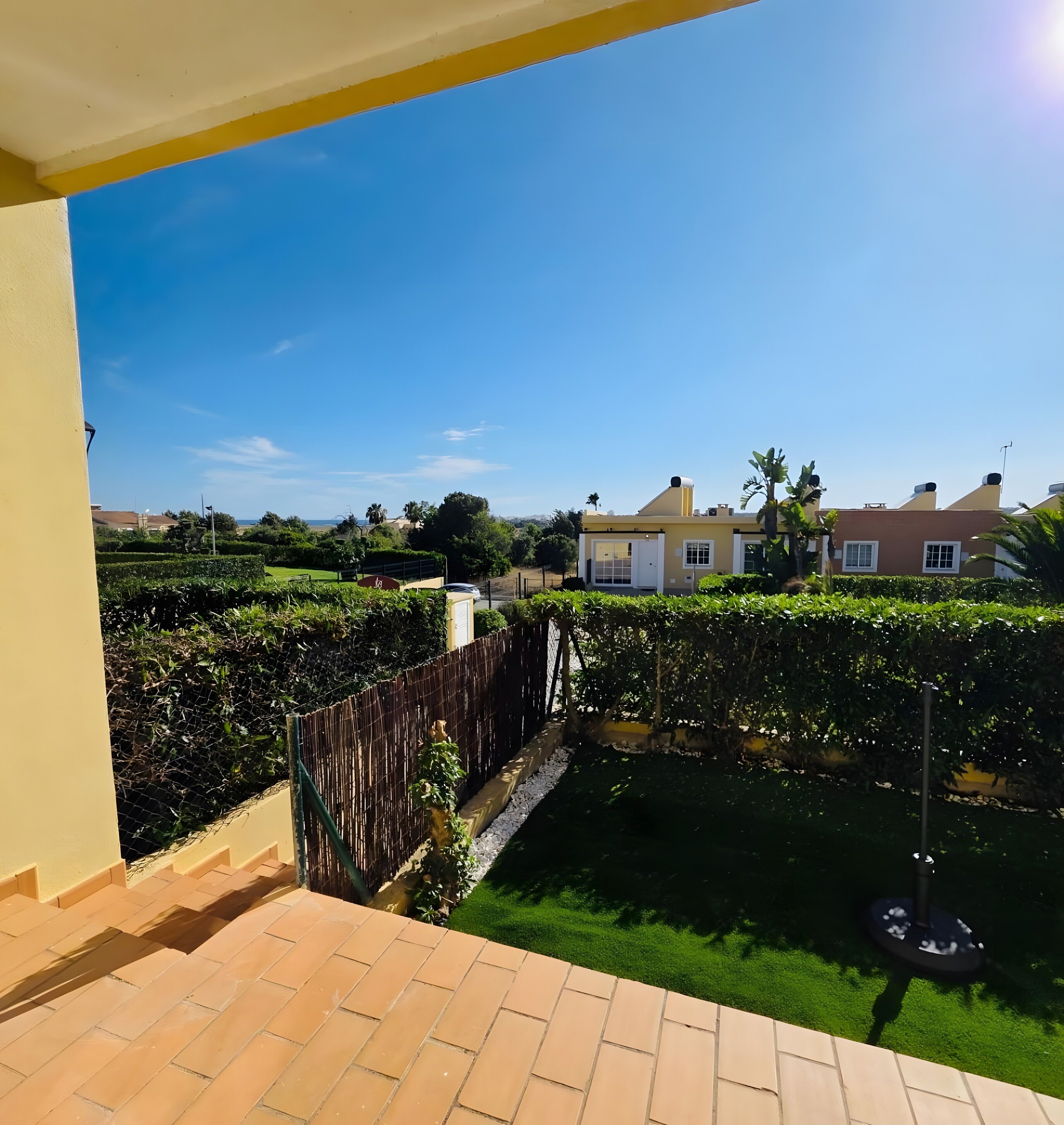 A residential area with a paved patio, a bamboo fence, and a well-maintained lawn.