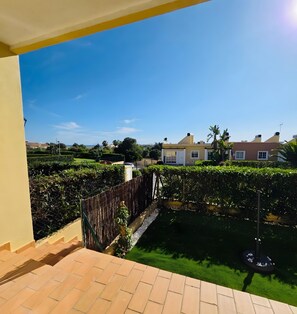 A residential area with a paved patio, a bamboo fence, and a well-maintained lawn.