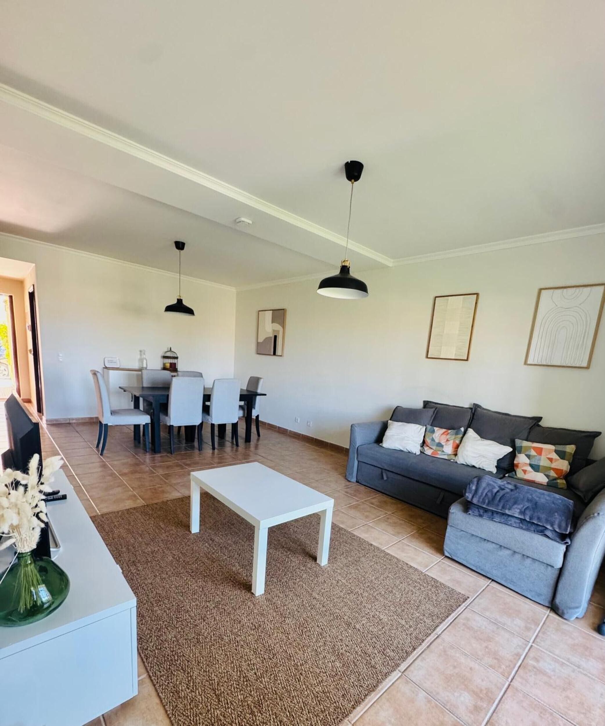 Een woonkamer met een bank, een salontafel en een eethoek met stoelen en een tafel.
