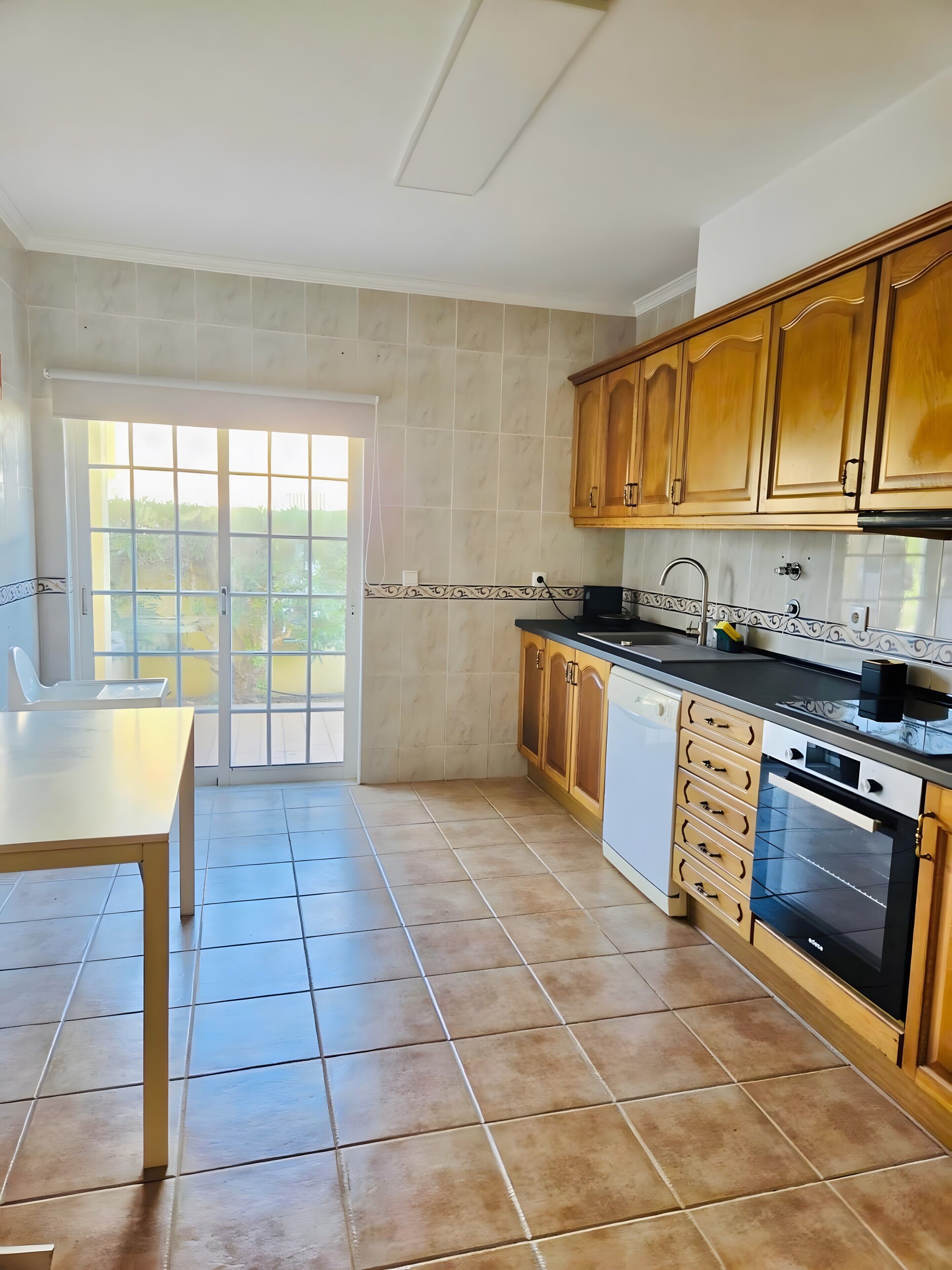 A kitchen with a dining table, cabinets, and a built-in oven.