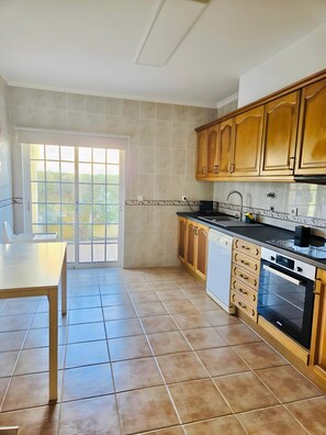 A kitchen with a dining table, cabinets, and a built-in oven.
