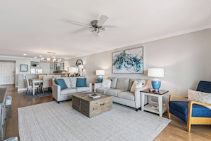 A modern living room with a sofa, coffee table, and a dining area in the background. - Pier Pointe Oceanfront Condo in the Village, sleeps 4 (St Simons Island)