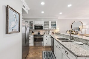 A modern kitchen with stainless steel appliances, white cabinetry, and a granite countertop. - Pier Pointe Oceanfront Condo in the Village, sleeps 4 (St Simons Island)