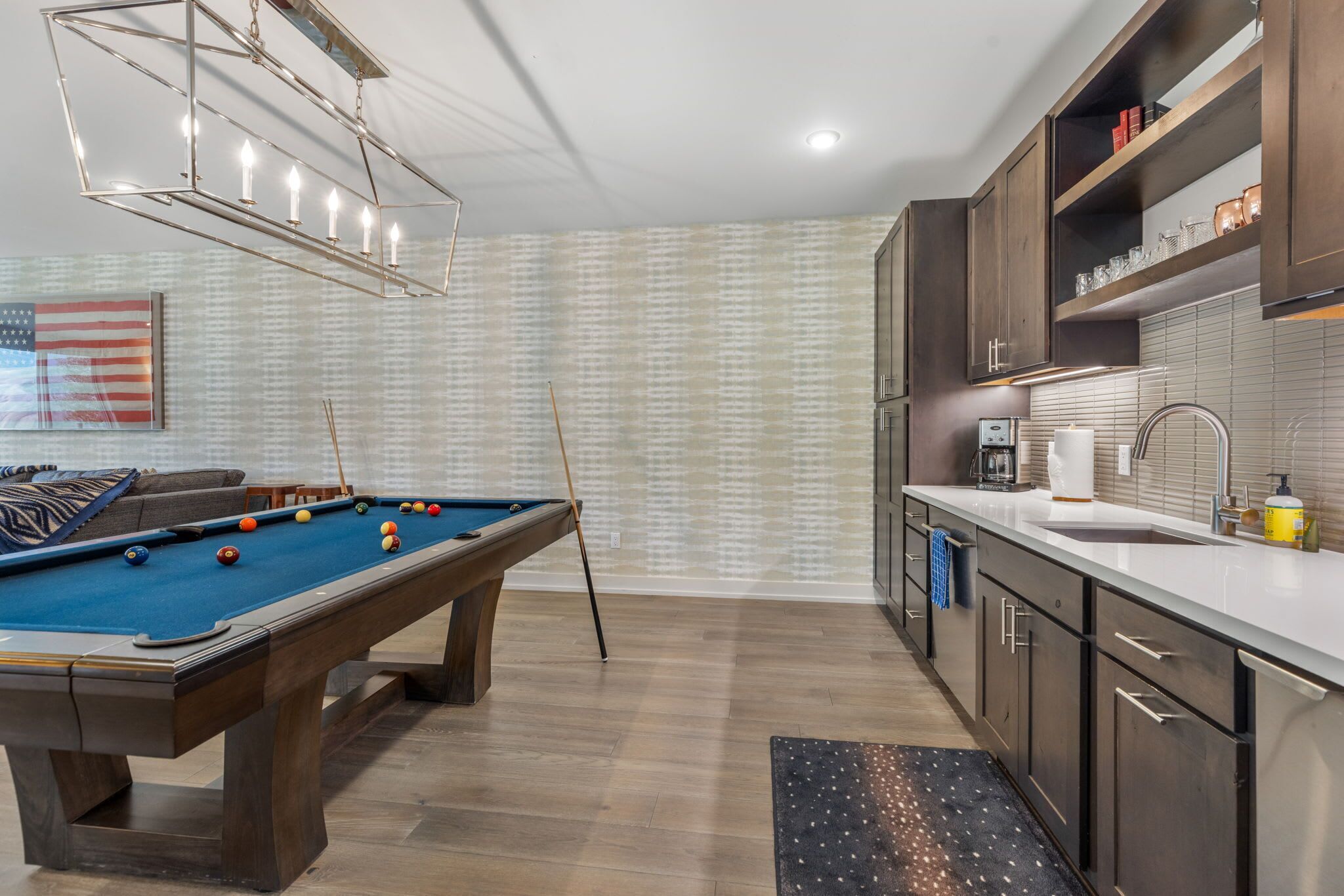 A modern kitchen with a pool table, wooden cabinets, and a coffee machine.