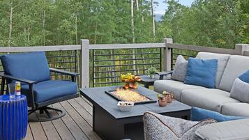 A deck with a fire feature, seating, and a table with drinks.