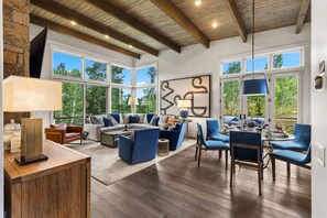A spacious living room with a high ceiling, large windows, and a modern fireplace. - Ultra Luxury Retreat - Private Hot Tub, Firepits (Silverthorne)