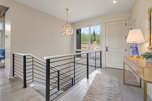 A modern interior with a staircase, a view to the outside, and a lamp on a wooden table. - Ultra Luxury Retreat - Private Hot Tub, Firepits (Silverthorne)