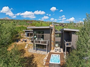 Una casa moderna de dos pisos con terraza, mobiliario exterior y un jacuzzi.