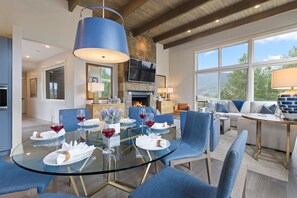 Un comedor moderno con una mesa de vidrio, sillas azules y una chimenea.