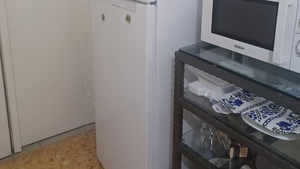 A kitchen with a white refrigerator, a microwave, and a glass-top table with dishes. - B&B TETYANa (Naples)