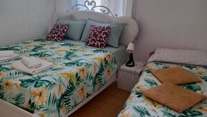 A bedroom with two beds, a nightstand, and a window with curtains. - B&B TETYANa (Naples)