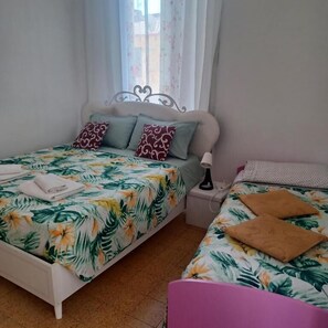 A bedroom with two beds, a nightstand, and a window with curtains. - B&B TETYANa (Naples)