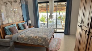 Un dormitorio con cama, mesita de noche, armario de madera y vistas al exterior mediante una puerta corrediza.