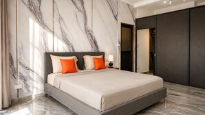 Un dormitorio moderno con una cama grande, paredes de mármol y un armario oscuro.