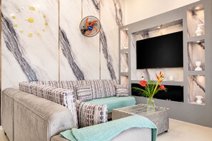 A modern living room with a sofa, coffee table, and a TV mounted on the wall.