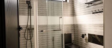 A modern bathroom with a glass-enclosed shower, a black toilet, and a towel rack.