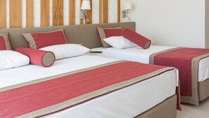 A hotel room with two beds, each with red and white bedding, and a wooden headboard.
