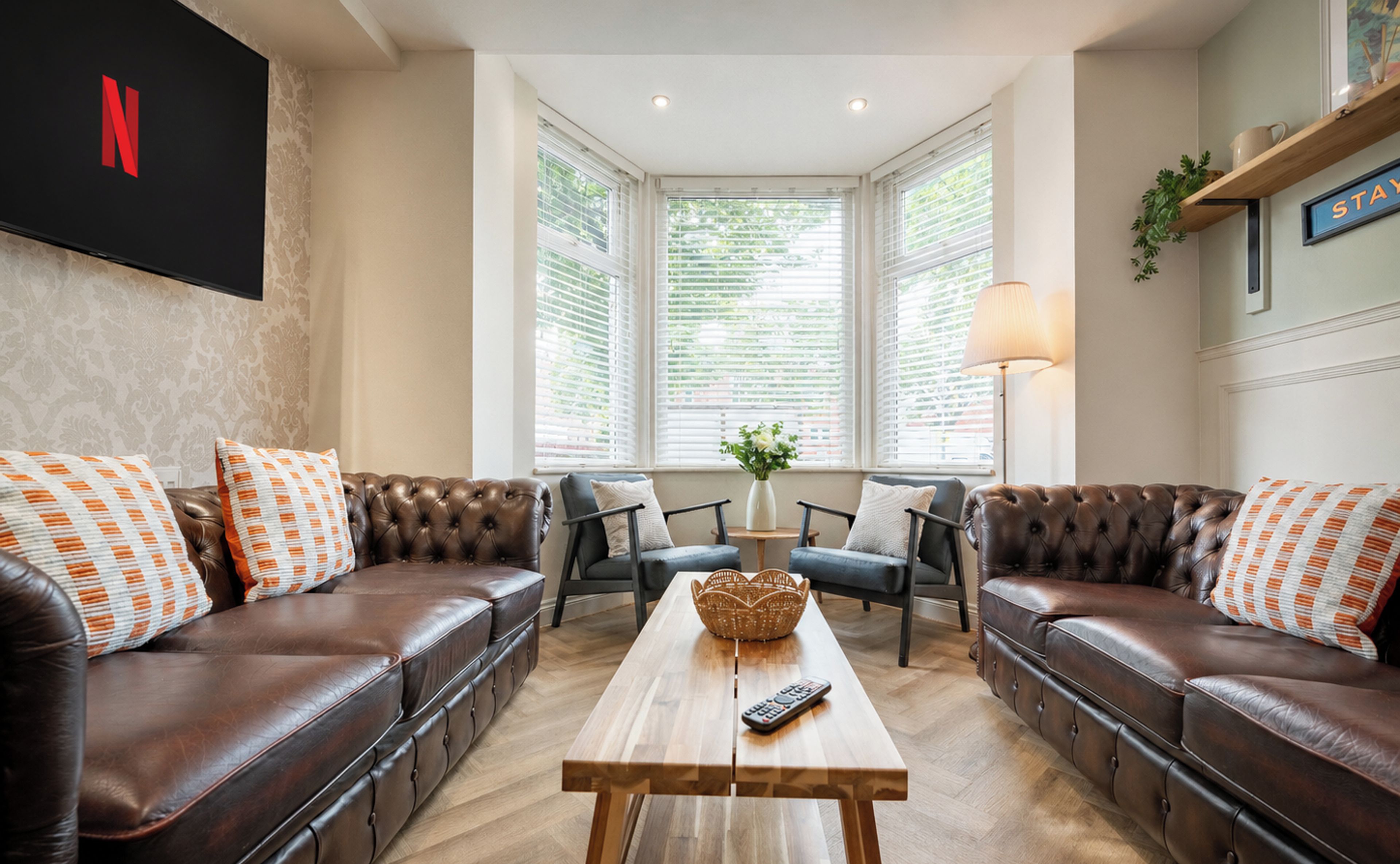 A living room with leather sofas, a wooden coffee table, and a TV mounted on the wall.