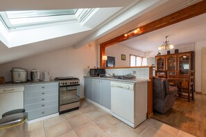 Cocina compacta con tragaluz, comedor con mesa y sillas de madera, y un mueble empotrado con puertas de vidrio.