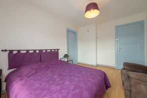 A bedroom with a bed, a nightstand, a lamp, and two doors. - Apartment 'Maison De Vacances Dans Les Vosges' with Mountain View, Private Terrace and Wi-Fi (Granges-Aumontzey)