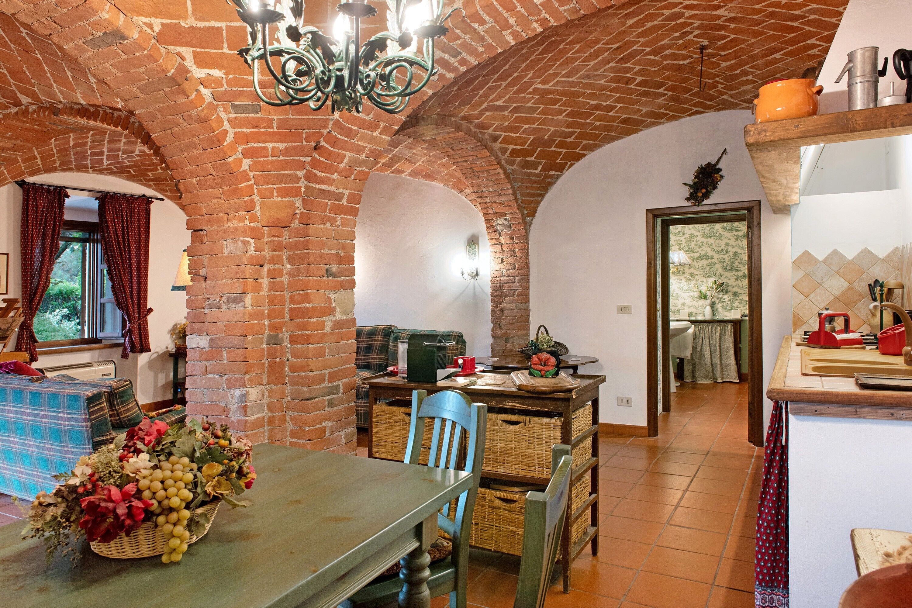 A rustic kitchen with exposed brick walls, a dining table with chairs, and a variety of kitchen utensils and appliances.