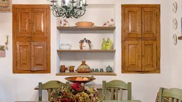 A dining area with wooden cabinets, a chandelier, and a table set with a fruit basket.