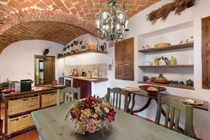 A rustic kitchen with a brick ceiling, wooden cabinets, and a dining table set with chairs.