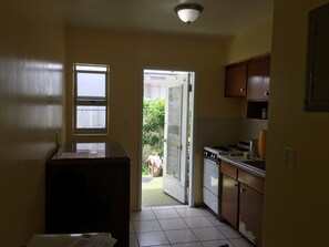 A kitchen with a stove, cabinets, and a window. - BEACH Studio #2 The Village of Lauderdale-by-the-Sea (Lauderdale-by-the-Sea)