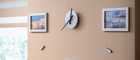 Un reloj de pared de diseño minimalista, rodeado de cuatro cuadros enmarcados que muestran arquitectura histórica.