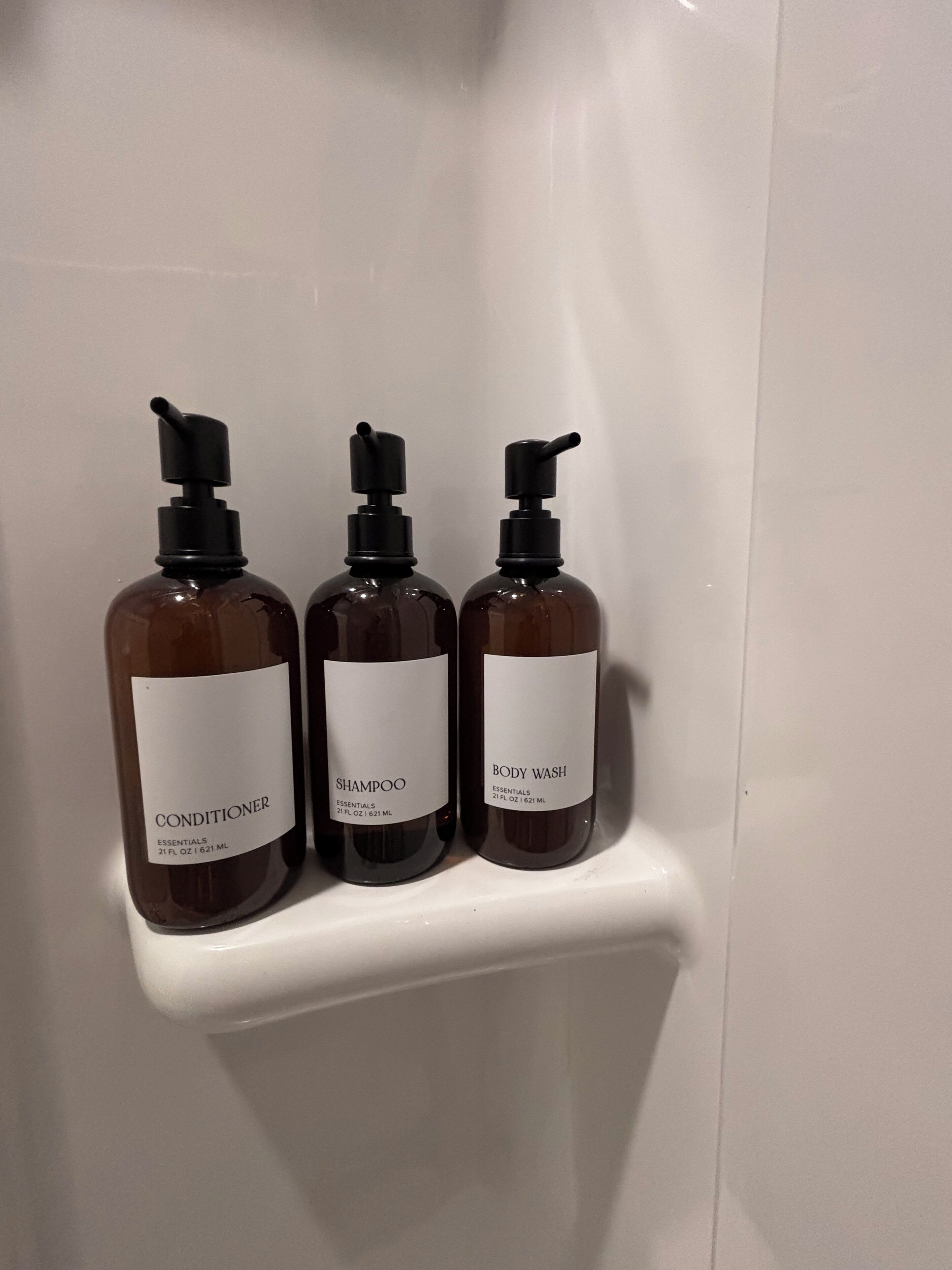 Drie flessen toiletartikelen op een witte plank.