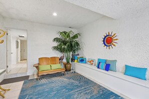 A spacious living area with a wooden bench, a large potted plant, and a decorative wall piece.