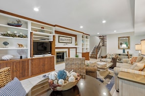A spacious living room with a fireplace, a television, and a staircase leading to another level.