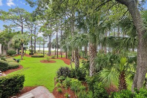 A landscaped garden with a variety of trees, a well-maintained lawn, and a brick pathway. - Gorgeous Villa w/ Panoramic Views (Hilton Head Island)