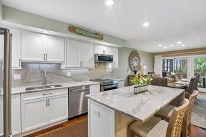 A modern kitchen with white cabinets, a stainless steel dishwasher, and a marble countertop. - Gorgeous Villa w/ Panoramic Views (Hilton Head Island)