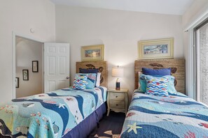 A bedroom with two beds, a nightstand, a door, and framed pictures on the wall. - Gorgeous Villa w/ Panoramic Views (Hilton Head Island)
