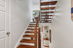 A staircase with wooden steps and a handrail, leading to a landing with a view of the outdoors.