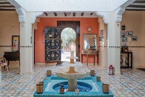 A lobby with a fountain, tiled floor, and a door leading outside.