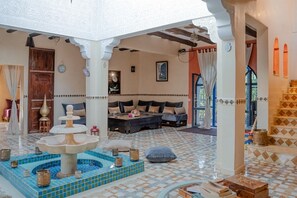 A traditional interior with a fountain, seating area, and decorative tiles.
