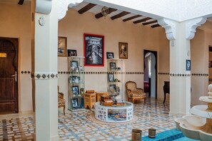 A lobby with a checkered floor, a round coffee table, and a large framed picture on the wall.