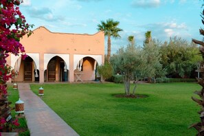 A building with a flat roof, multiple arches, and a paved pathway leading to the entrance.