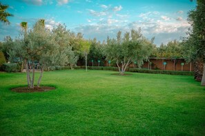 A well-maintained grassy area with trees and a brick wall in the background.