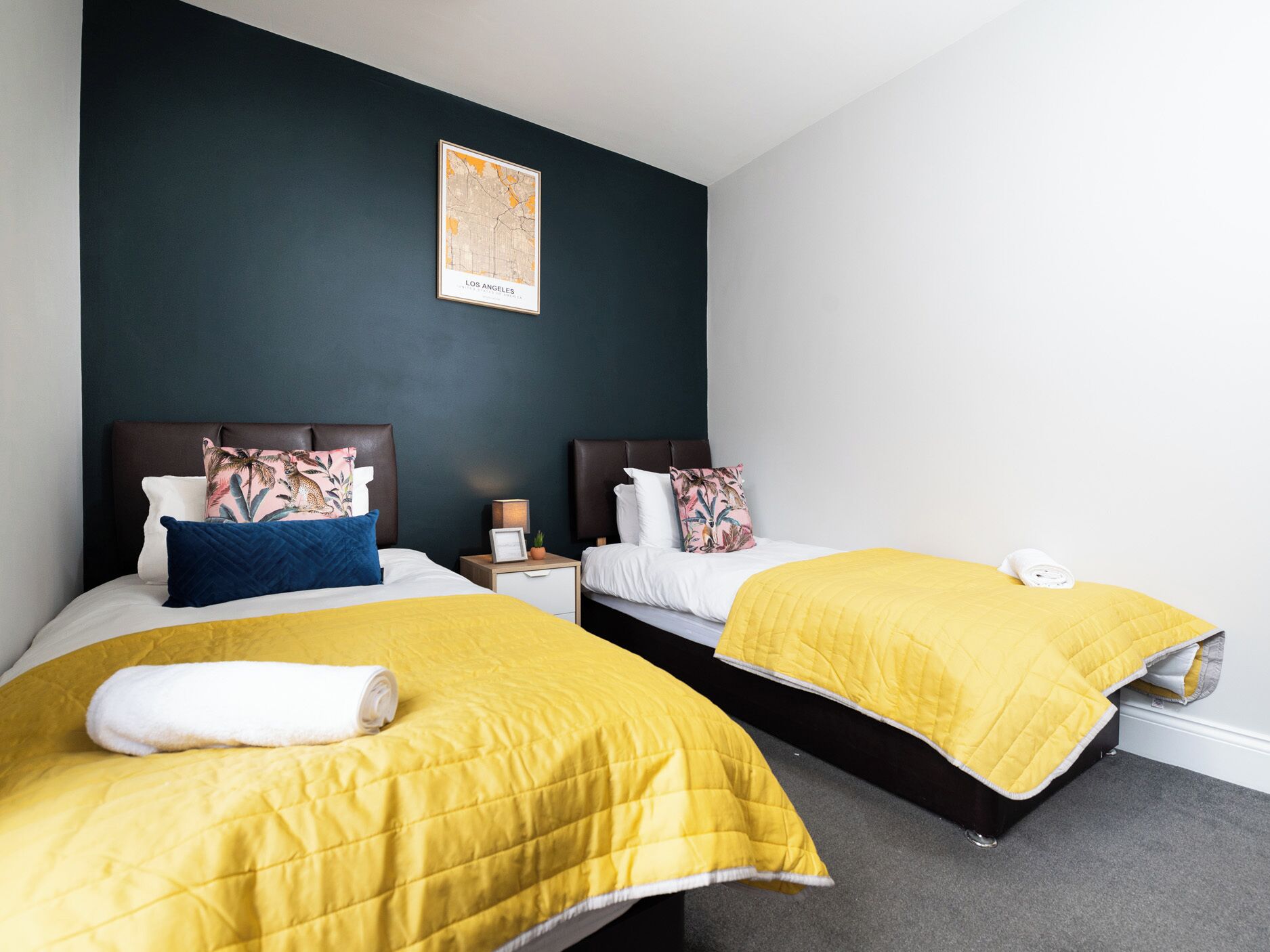 Een hotelkamer met twee bedden, donkere wanden en een kaart van Los Angeles aan de muur.